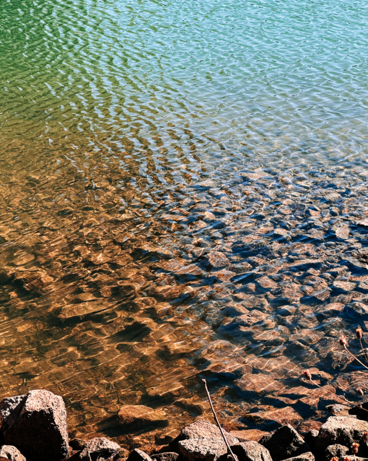 A 3/4 angle shot shows ripples of water over a rocky shore.