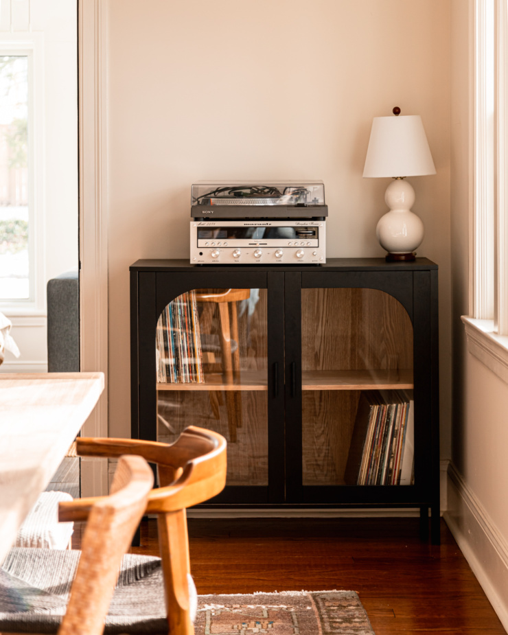 A head-on shot shows a matte black record player cabinet with a record player, receiver and lamp on top.