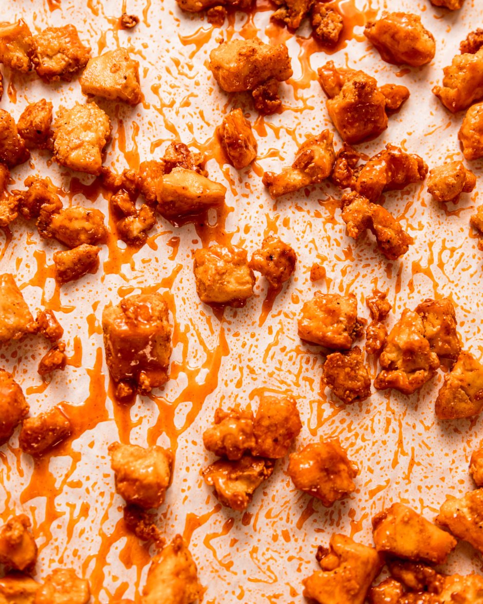 An overhead shot shows little baked bits of tofu freshly tossed in Buffalo-style hot sauce.