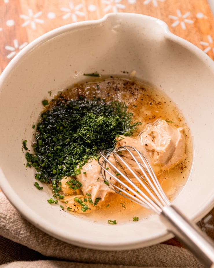 An overhead shot shows a small mixing bowl with a small whisk and ingredients for a vegan ranch dressing inside.