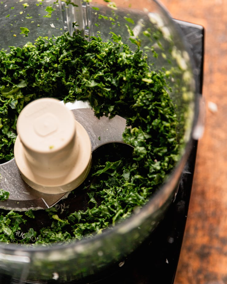 An overhead shot shows finely chopped kale in the food processor.