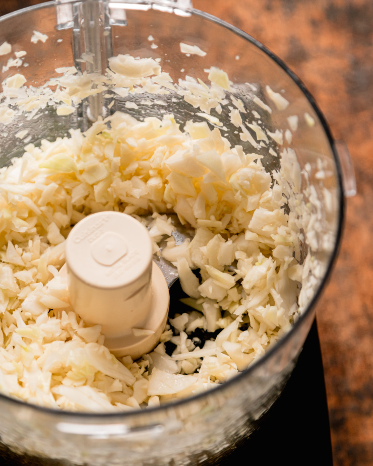 An overhead shot shows finely chopped cabbage in the food processor.