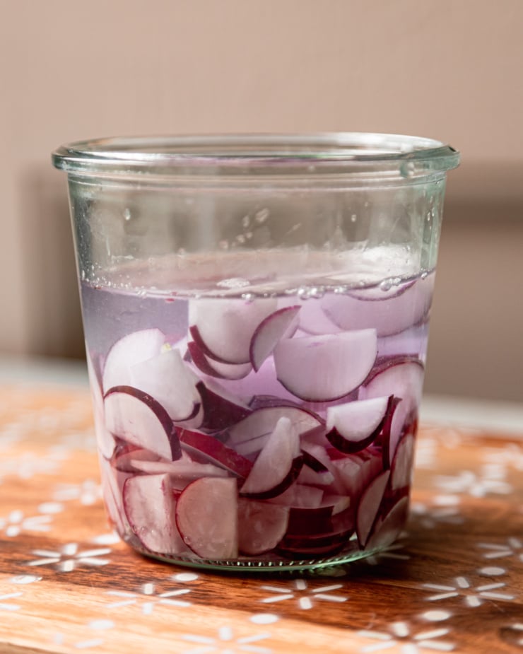 A head-on shot shows a jar with sliced radishes and water.