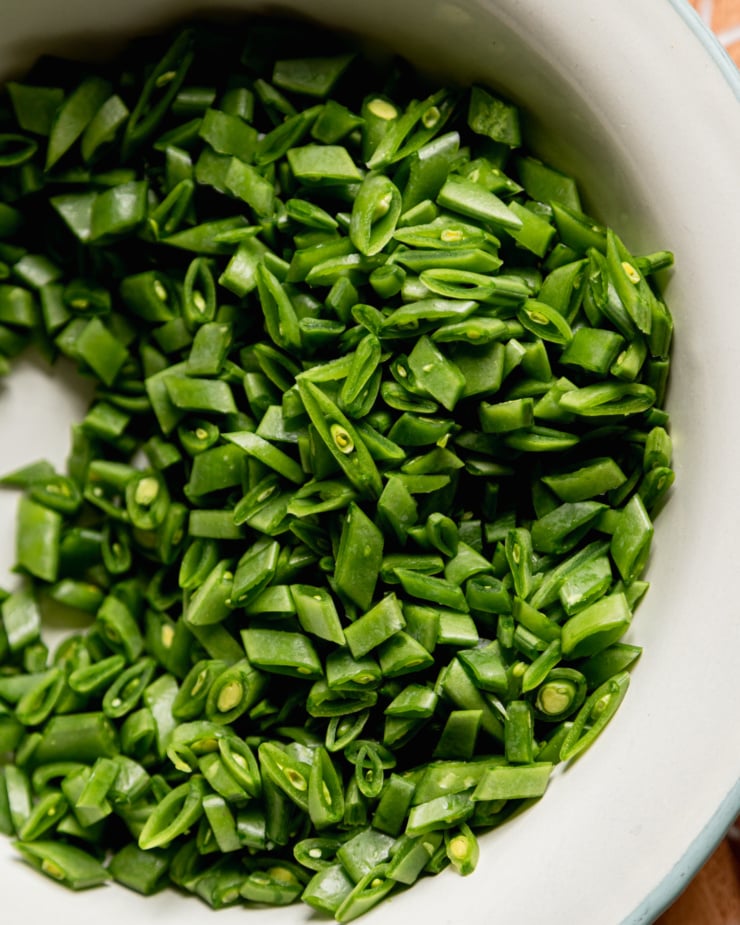 An overhead shot shows finely chopped snap peas in a bowl.