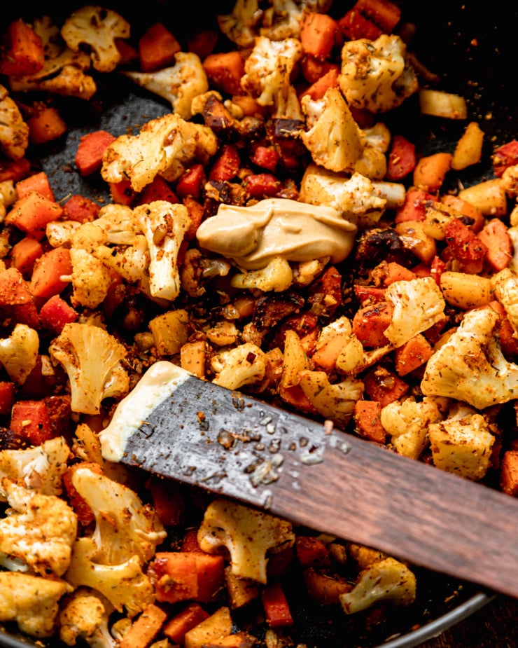 An overhead shot shows sautรฉed carrots and cauliflower with a dab of Dijon mustard on top.