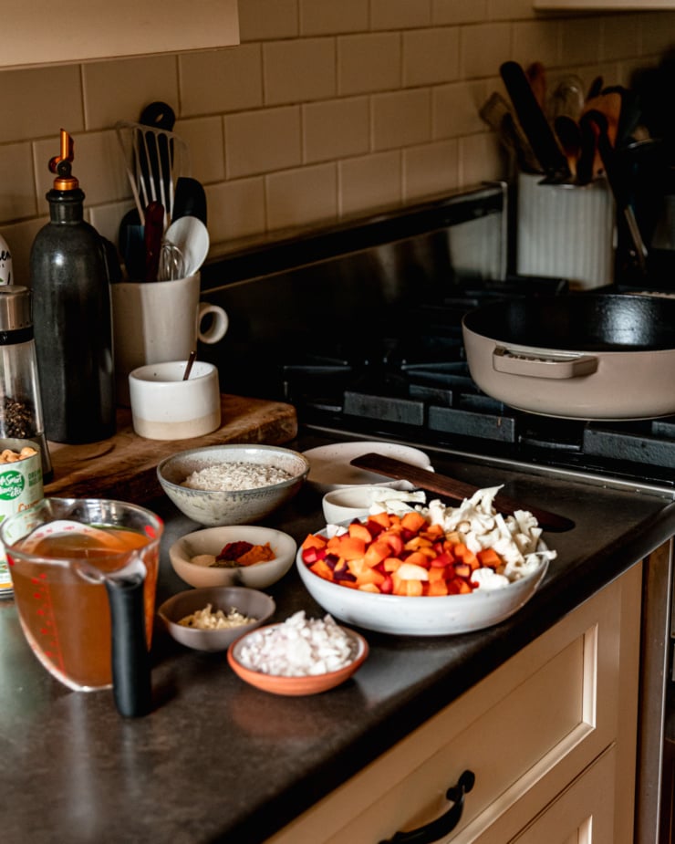 A head-on shot shows a kitchen counter near the stovetop. On the counter are [prepped ingredients for a vegetables and rice dish.