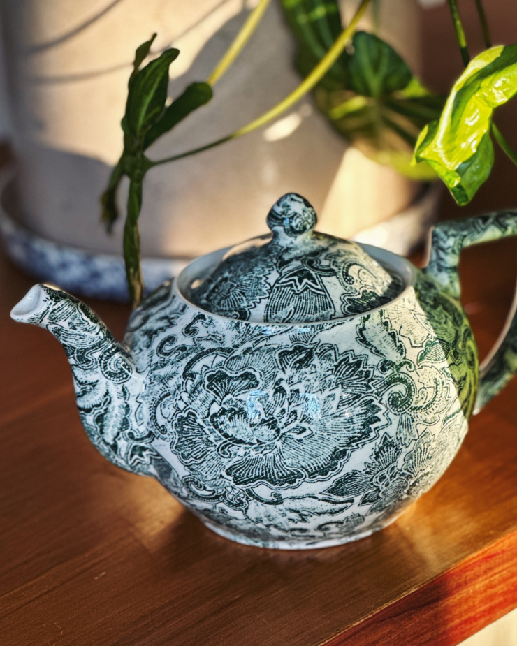 A 3/4 angle shot shows a ceramic teapot with a white and green peony motif.