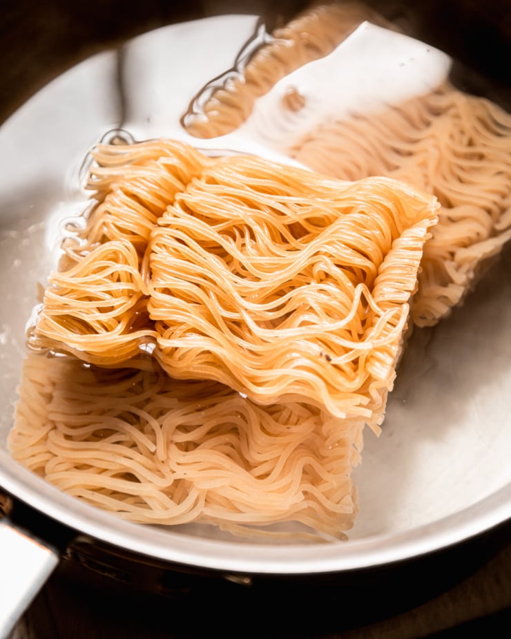 An up close, overhead shot shows "cakes" of ramen noodles in water.