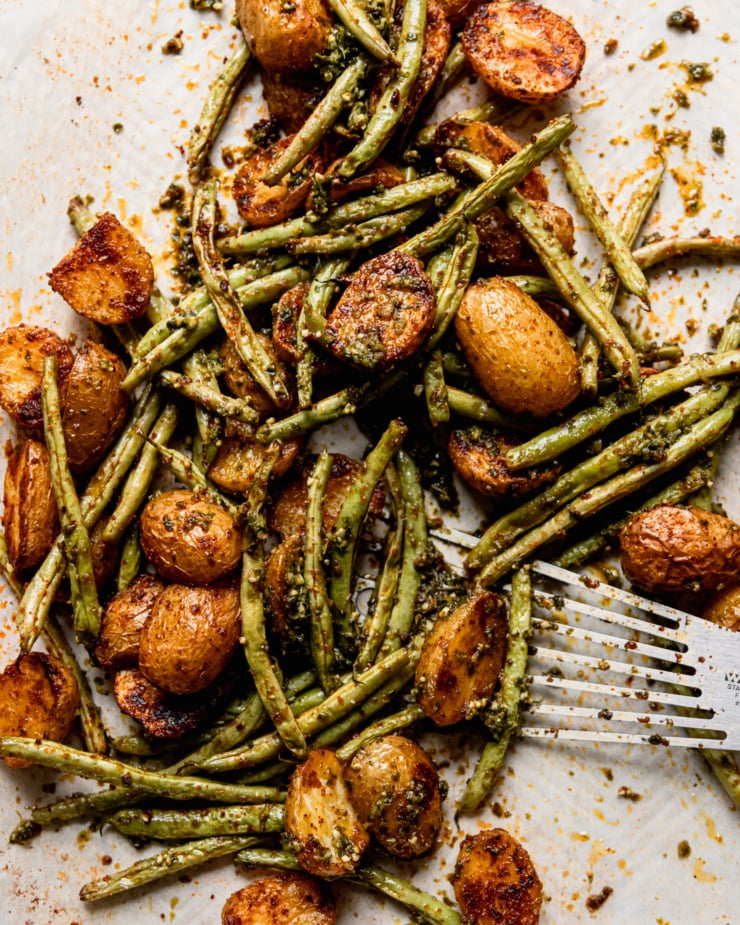 An overhead shot shows mixed roasted potatoes and green beans on a baking sheet.