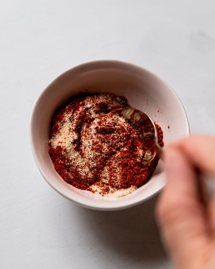 An overhead shot shows spices being stirred together in a small bowl.
