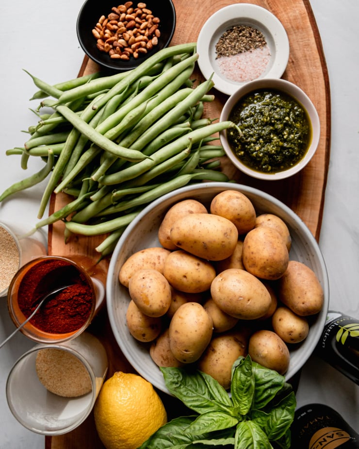 An overhead shot shows ingredients needed for a roasted fresh green beans and potatoes dish with pesto.