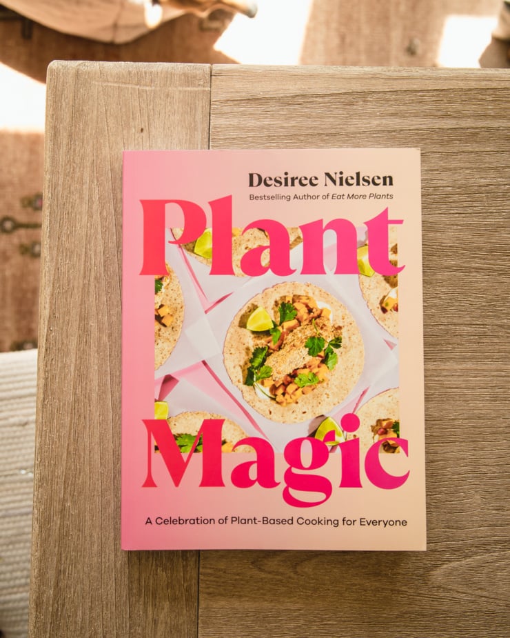 An overhead shot shows the cookbook cover of "Plant Magic" by Desiree Nielsen.