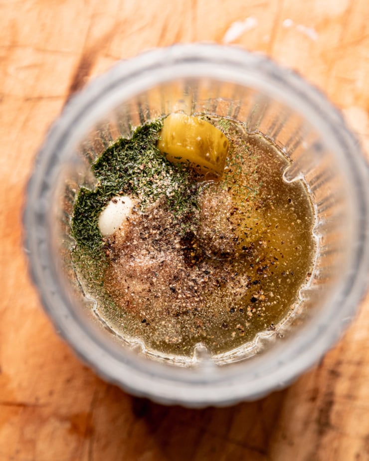 An overhead shot shows ingredients for a creamy dill pickle dressing in a blender container.