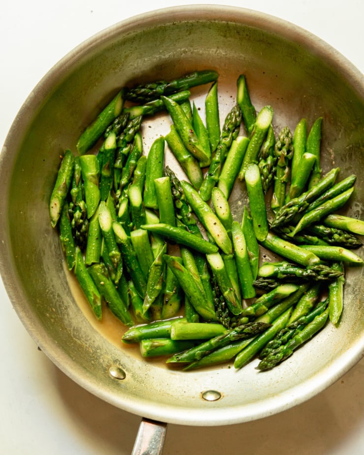An overhead shot shows sautéed asparagus in a sauté pan.