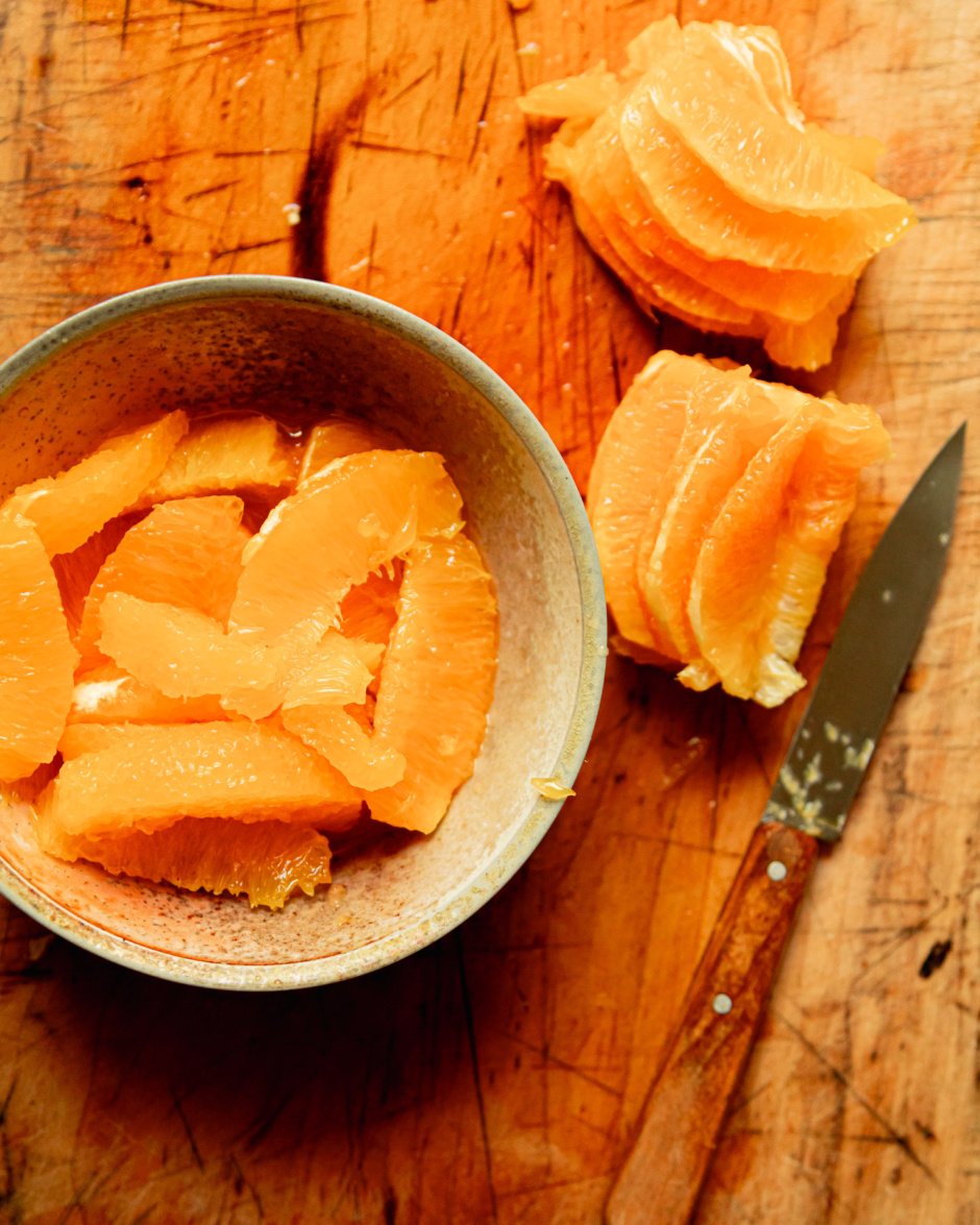 An overhead shot shows a bowl of orange supremes and the remaining pith/pulp etc of the oranges they were extracted from.
