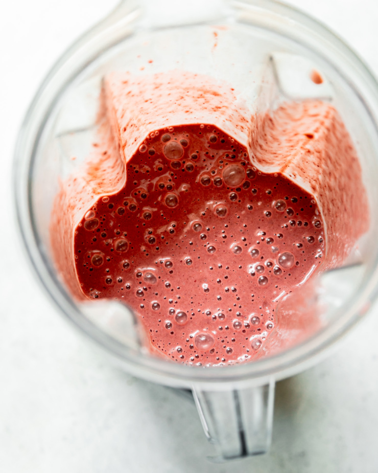 An overhead shot shows a blended up chocolate cherry smoothie in a blender pitcher.
