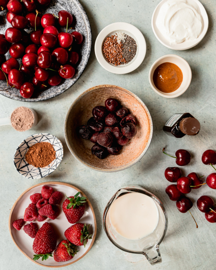 An overhead shot shows ingredients for a vegan cherry breakfast smoothie.
