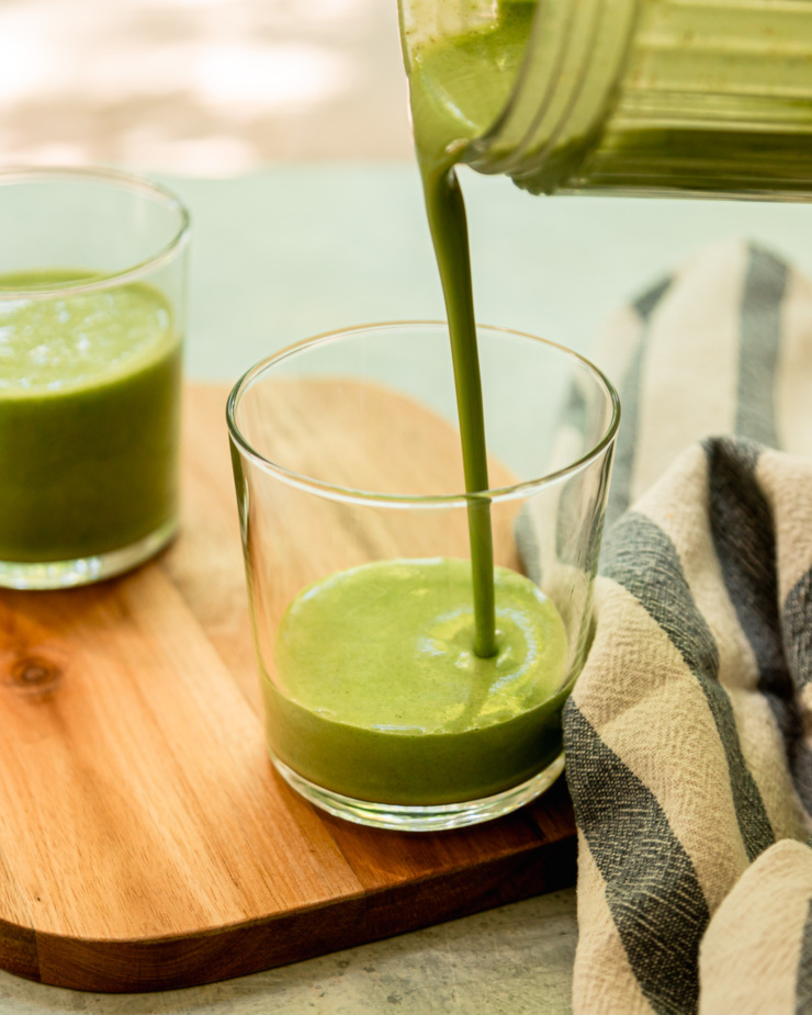 A 3/4 angle image shows a green peanut butter smoothie being poured into a glass.