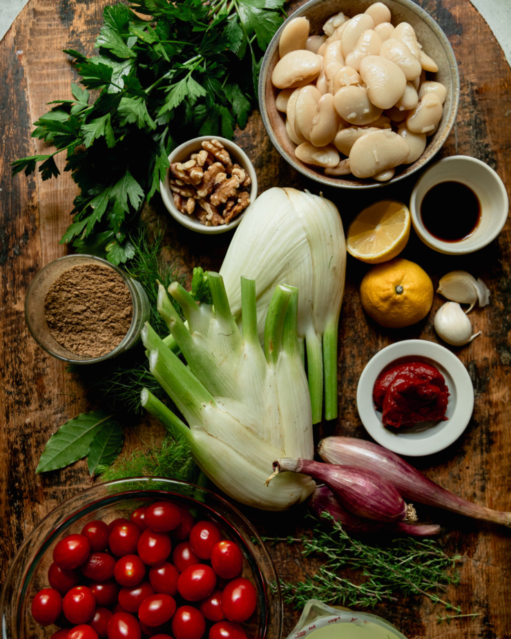An overhead shot shows ingredients for a vegan one skillet dinner featuring cherry tomatoes, fennel, and butter beans.