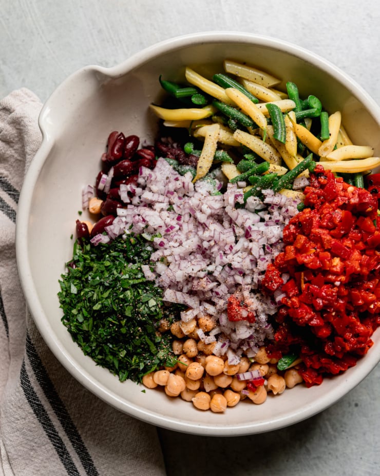 An overhead shot shows all ingredients for a four bean salad in a large bowl, prior to being mixed up.