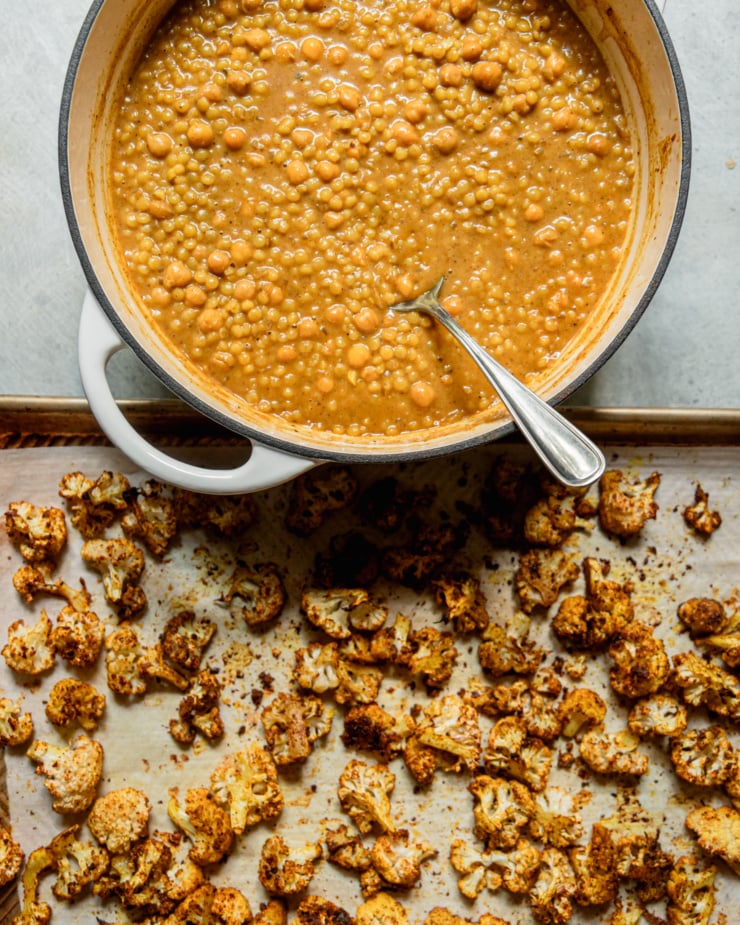 An overhead shot shows a pot of spiced coconut couscous and a tray of roasted cauliflower.