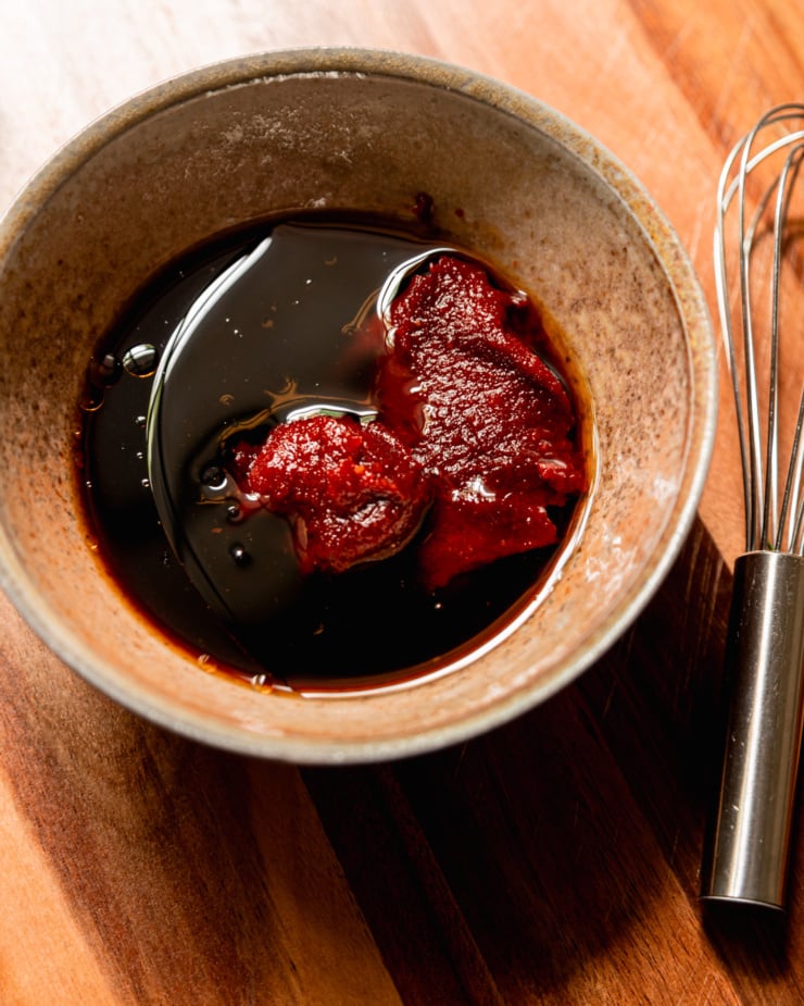 An overhead shot shows a bowl with ingredients for a gochujang glaze, prior to mixing together.