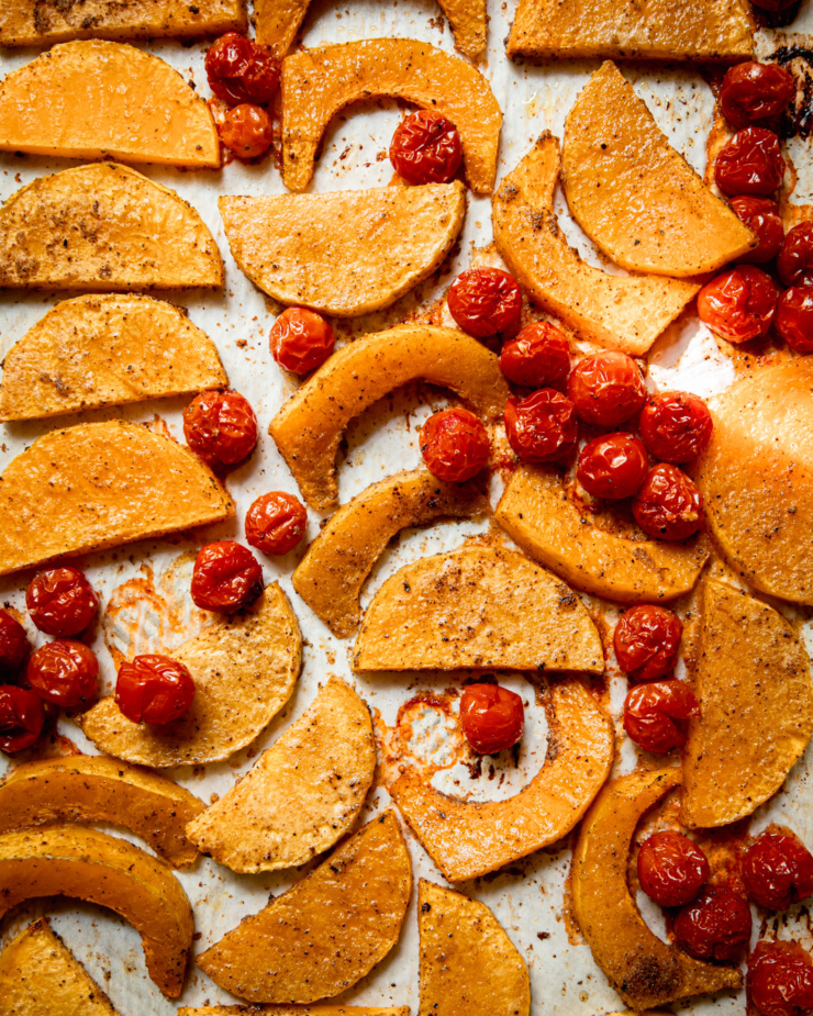 An overhead shot shows roasted slices of butternut squash and burst cherry tomatoes on a sheetpan.
