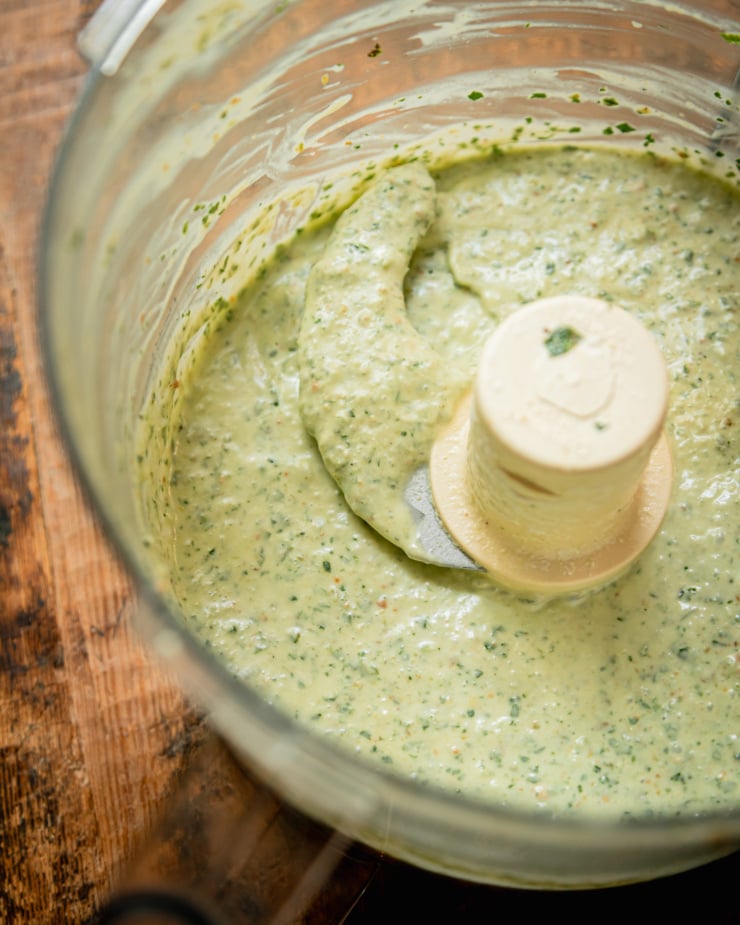 An overhead shot shows a pale green vegan yogurt sauce that has just been mixed up in a food processor.