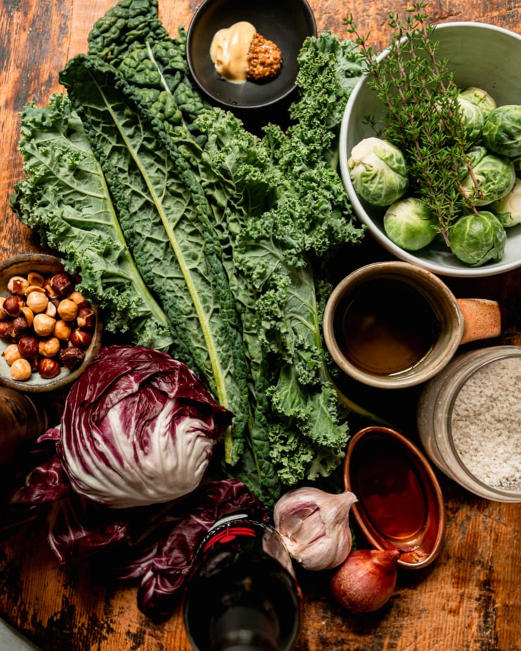 An overhead shot shows ingredients for a salad with kale, radicchio, brussels sprouts, and a sherry thyme vinaigrette.