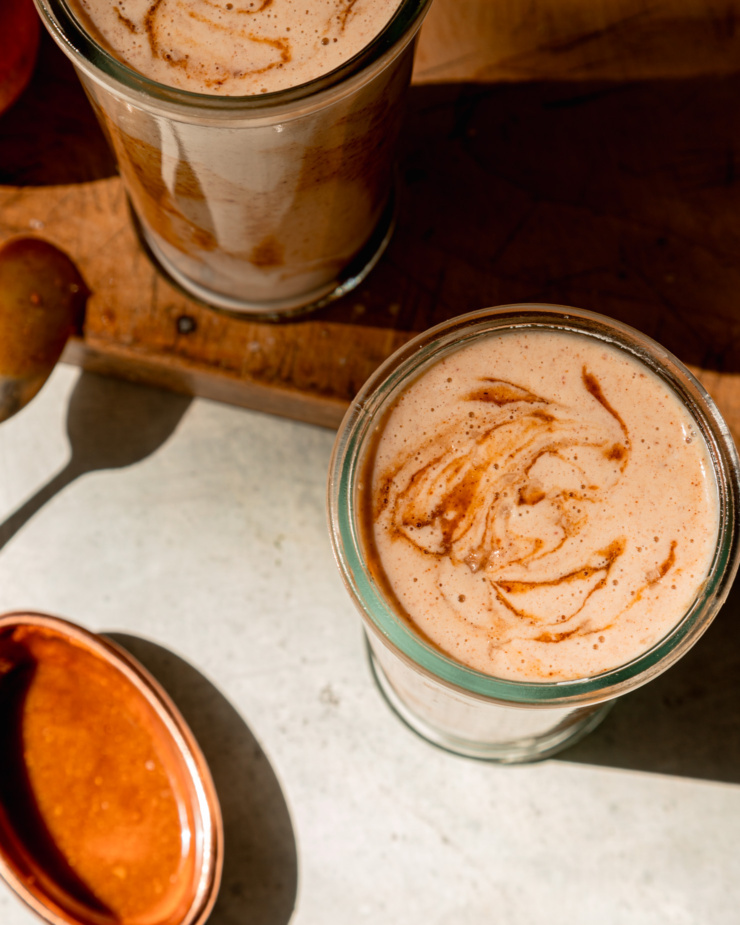 An overhead shot shows two smoothies with almond butter "caramel" drizzles swirled into the top.