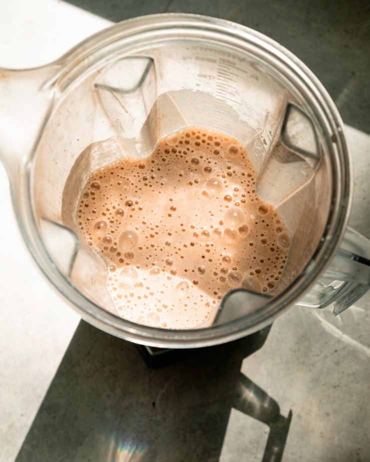 An overhead shot shows a blended up apple smoothie in a blender pitcher.