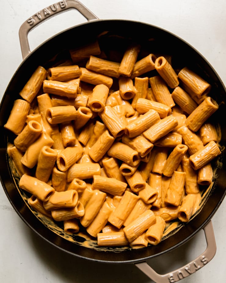 An overhead shot shows a creamy vegan butternut squash pasta in a braiser-style pot.