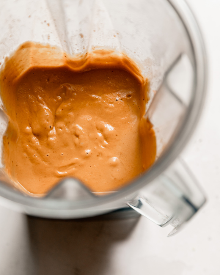An overhead shot shows a blended butternut squash pasta sauce in a blender pitcher.