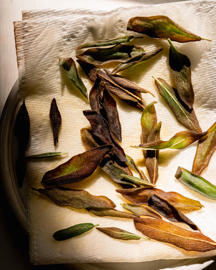 An overhead shot shows fried sage leaves draining on a paper towel.
