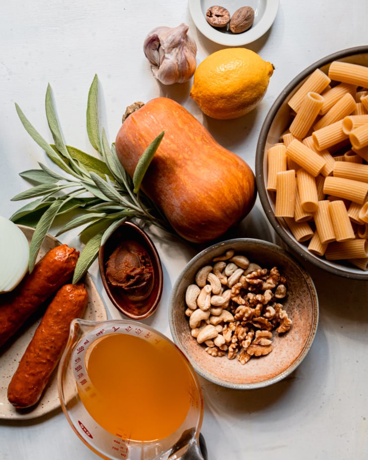 An overhead shot shows ingredients for a vegan butternut squash pasta with veggie sausage and sage.