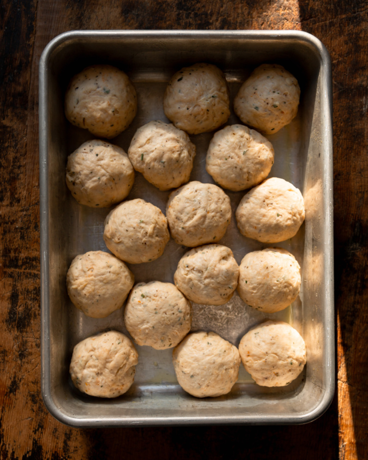 An overhead shot shows portioned balls of dough in a metal 9x13 baking dish.
