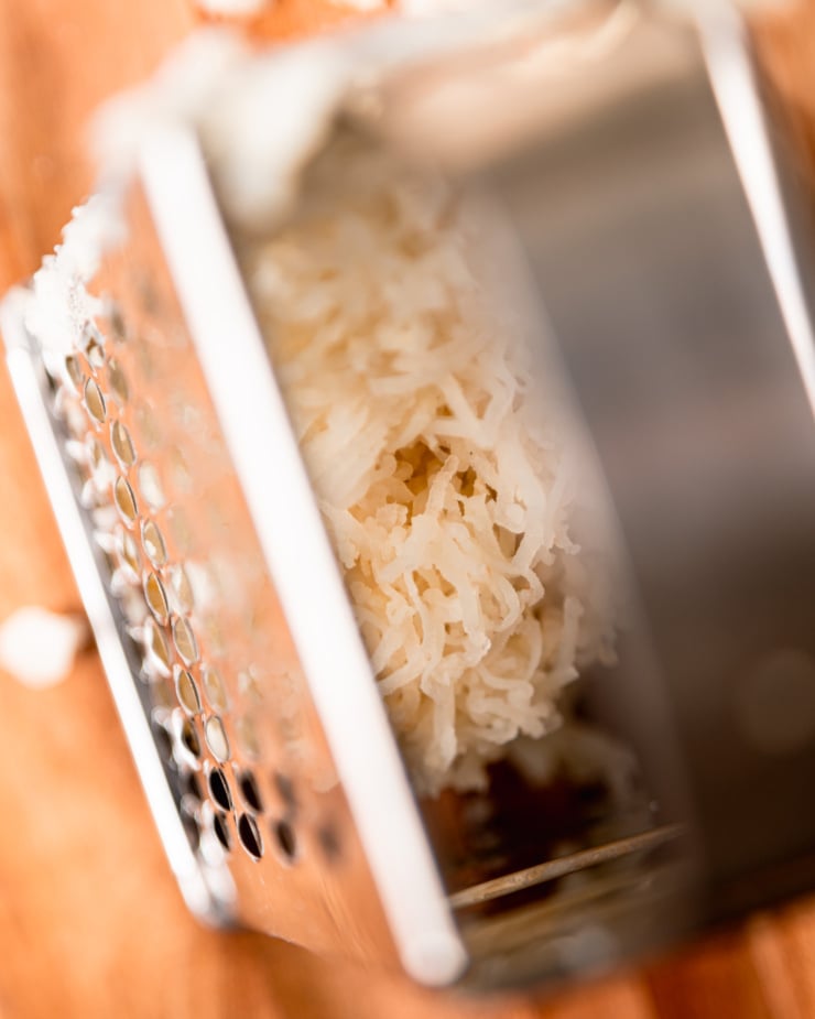 An up close, overhead shot shows fine shreds of cooked russet potato inside of a box grater.