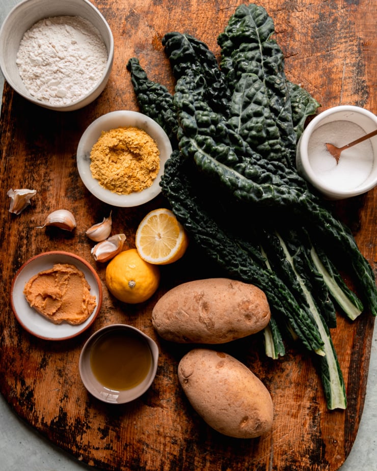 An overhead shot shows ingredients needed for vegan potato gnocchi with kale sauce.