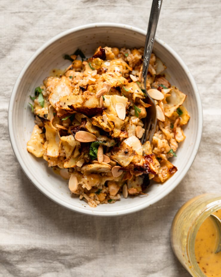 An overhead shot shows an individual serving of a rice, chickpea, and cabbage dish. A jar of sweet mustard dressing is nearby.