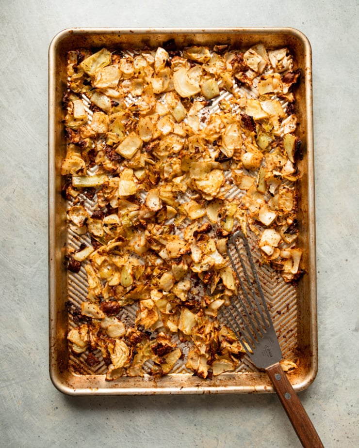 An overhead shot shows a baking sheet of crispy roasted cabbage with a fish spatula.