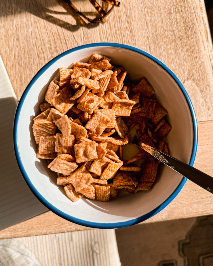 An overhead shot shows a bowl of Cinnamon Crunch cereal in a bowl in bright sunlight.