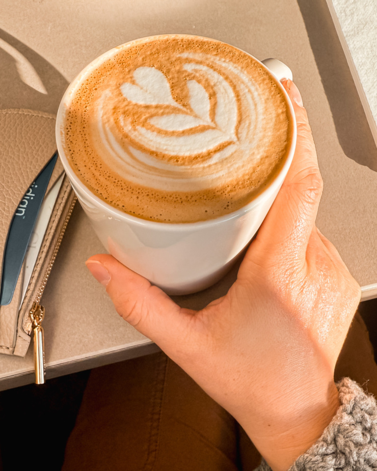 An overhead shot shows a hand holding a latte in a mug.