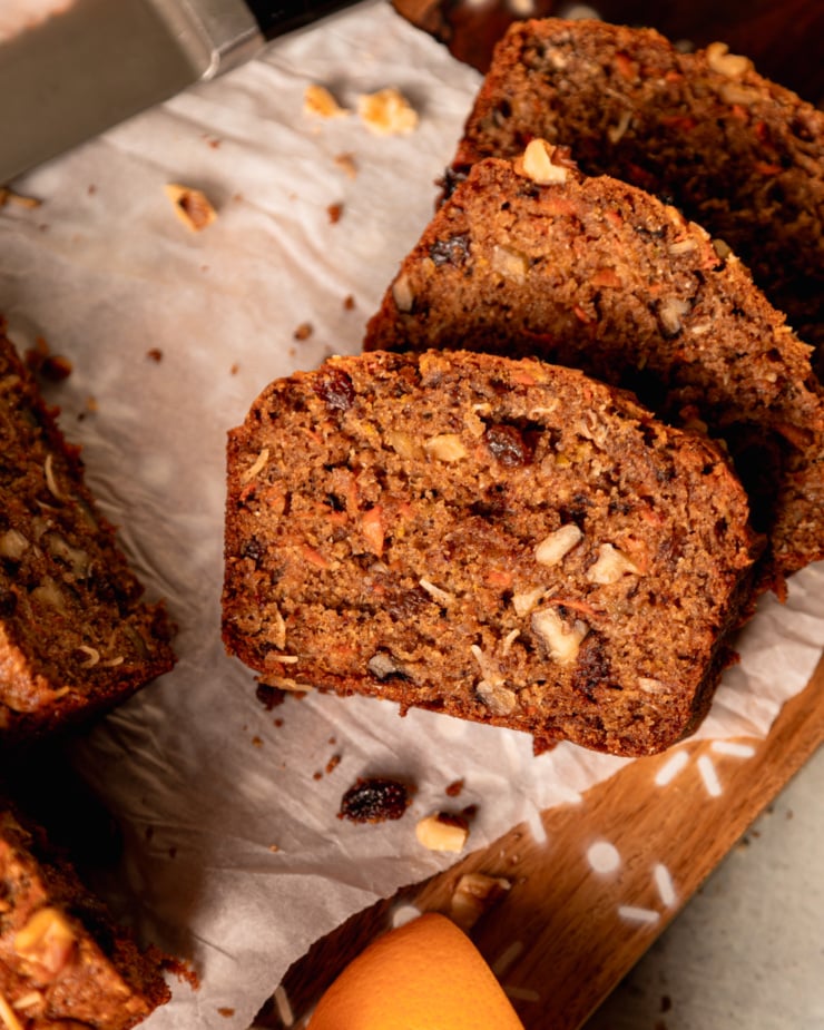 An overhead shot shows sliced of a morning glory loaf on crinkled up parchment paper.