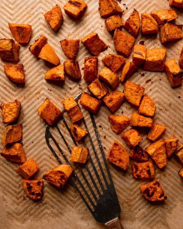 An overhead shot shows roasted sweet potatoes on a baking sheet with a metal spatula.