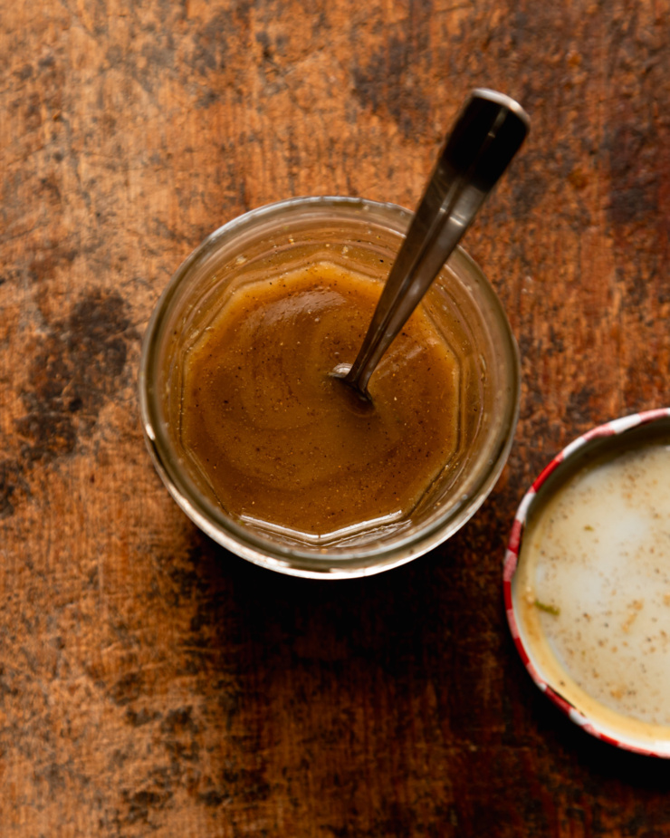 An overhead shot shows a jar with a sesame lime dressing inside. A spoon is sticking out of the jar.