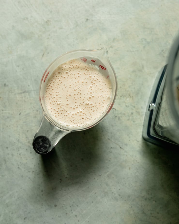 An overhead shot shows a cup of homemade cashew cream.