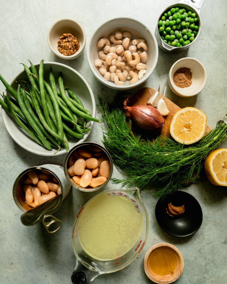 An overhead shot shows ingredients needed for a creamy and dilly beans and peas dish.