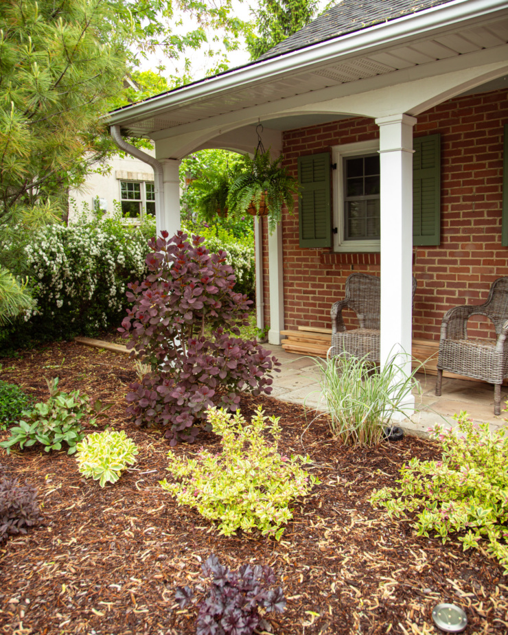 A head-on shot shows a garden in front of a brick home.