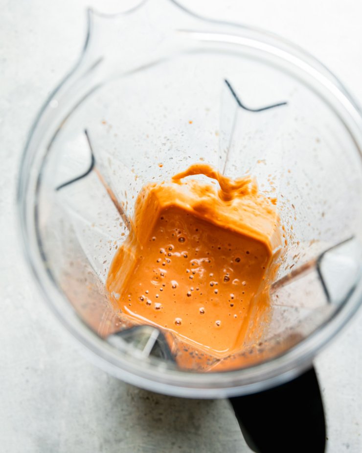 An overhead shot shows blended peanut sauce in a blender pitcher.