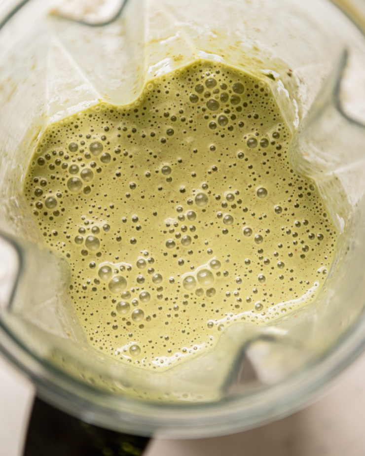 An overhead shot shows a blender pitcher filled with a matcha banana breakfast smoothie blend.